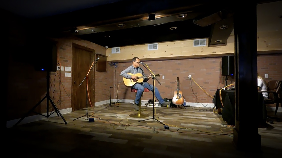 Michael Peter Ashley playing solo acoustic guitar on stage
